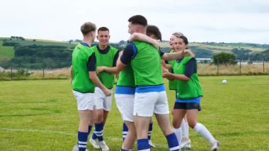 Futbol takımı zaferi çimenli sahada takım arkadaşını kaldırarak kutluyor. Kutlama, takım çalışması, sportmenlik, takım ruhu, dostluk, başarı.