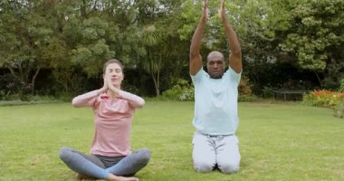 Barışçıl bahçede meditasyon yapan çok ırklı bir çift birlikte farkındalık ve rahatlama pratiği yapıyorlar. Meditasyon, sükunet, sağlık, maneviyat, zen, uyum.