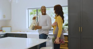 Mutfakta paketleri boşaltan çok ırklı bir çift evde, evde birlikte vakit geçiriyorlar. iç, ev, ilişki, bağ, takım çalışması