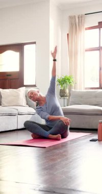 Dikey video: Yaşlı kadın paspasın üzerinde yoga yapıyor, barışçıl egzersizin tadını çıkarıyor. Sağlık, rahatlama, meditasyon, esneme, zindelik, sağlık