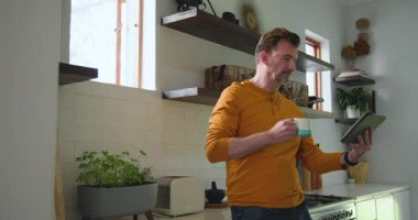 Evde kendini rahat hissedip tablet okurken mutfakta kahvenin tadını çıkaran son sınıf öğrencisi. teknoloji, sabah, rahatlama, yaşam tarzı, rahatlık, evcil