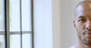 Afro-Amerikalı adam pencerenin yanında duruyor, düşünceli ve rahat görünüyor, fotokopi odası. Düşünce, rahatlama, yaşam tarzı, yalnızlık, yansıma, kapalı alan