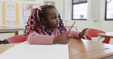 Sınıfta, Afrika kökenli Amerikalı kız not defterine yazıyor, işine odaklanıyor, okulda. Eğitim, öğrenim, öğrenim, odaklanma, ev ödevi, okul