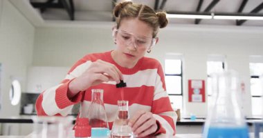 Okulda bilim deneyi yaparken, güvenlik gözlüğü takan ve odaklanmış genç bir kız. lab, eğitim, araştırma, öğrenme, kimya, koruyucu