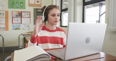Video konuşmasında, sınıfta ve okulda kulaklık takan genç bir kız. uzak öğrenim, teknoloji, eğitim, öğrenim, sanal sınıf, e-öğrenim