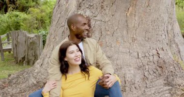 Ağacın altında rahatlayan, parktan ve birbirlerinin arkadaşlığından zevk alan çok kültürlü bir çift. Rahatlama, birliktelik, ilişki, açık hava, arkadaşlık, huzur