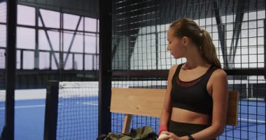 Kahve fincanı tutan kadın, takım arkadaşıyla kapalı sahada yapılacak Padel tenis maçına hazırlanıyor. Spor, atletik, takım çalışması, fitness, rekabet, hazırlık