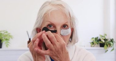 Son sınıf öğrencisi kadın cilt bakımı için göz altı bandı kullanıyor. Güzellik, kendine dikkat, yaşlanma karşıtı, sağlık, şımartma, yüz bakımı