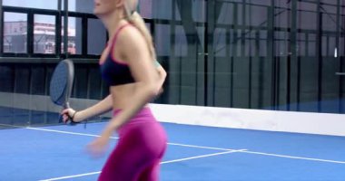 Kapalı alandaki mavi kortta Padel tenis oynayan odaklanmış bir adam, harekete hazır. Spor, atlet, raket, rekabet, fitness, konsantrasyon