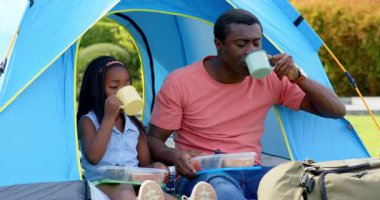 Afro-Amerikalı, baba-kız kamp çadırında piknik yapıyorlar. Aile, bağ, doğa, rahatlık, rahatlama.