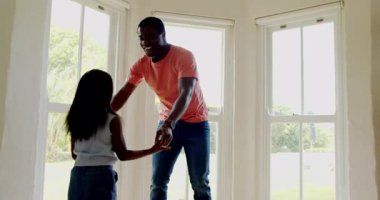 Afro-Amerikan, baba-kız evlerinde büyük pencerelerin yanında neşeyle dans ediyorlar. Aile, bağ, mutluluk, yaşam tarzı, kutlama, bağlantı