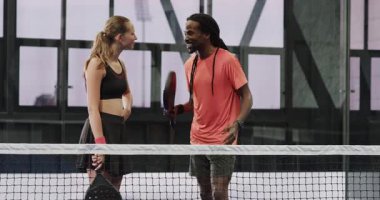 Gülen çeşitli sporcular, ellerinde raketlerle sahada Padel tenis stratejisini tartışıyorlar. Spor, takım çalışması, tartışma, atletik, açık hava, boş zaman