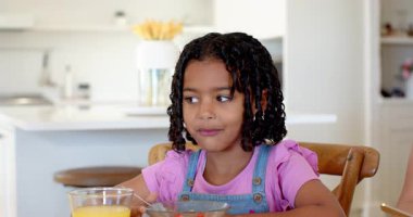 Afro-Amerikalı kız evde portakal suyu ve meyveyle kahvaltı yapıyor. Beslenme, sabah, içecek, sağlıklı beslenme, yaşam tarzı, yerli