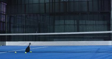 Padel tenis raketi ve toplar kalenin yanındaki mavi kortta, oyun için hazır, kopyalama alanı. Spor, ekipman, eğlence, eğlence, raket, rekabetçi