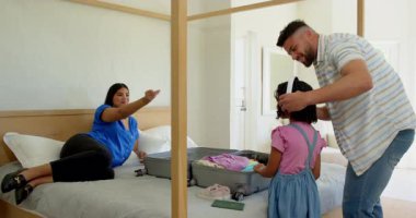 Aile bavullarını yatağın üzerine topluyor, heyecanla tatile hazırlanıyor. Seyahat, bagaj, yolculuk, hazırlık, yolculuk