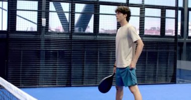 Kapalı alanda tenis oynayan, raket tutan ve maça odaklanan bir adam. Spor, atletizm, rekabet, konsantrasyon, egzersiz, raket