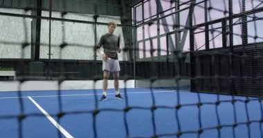 Kapalı alanda tenis oynayan genç adam, raketle topa vurmaya odaklanıyor. Spor, raket, aktif, rekabet, atlet, egzersiz