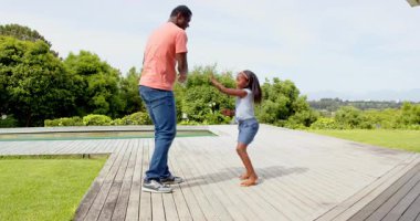 Afrikalı Amerikalı, baba ve kızı güneşli arka bahçede neşeyle dans ediyor. Aile, bağ, mutluluk, dans, yaz, açık hava