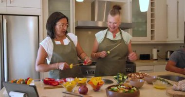 Çeşitli yaşlılardan oluşan bir grup modern mutfakta birlikte yemek pişiriyor, evde sohbetin tadını çıkarıyor. Yaşlı, takım çalışması, aşçılık, ev hayatı, çeşitlilik, yaşam tarzı