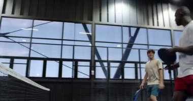 İki farklı adam kapalı alanda tenis oynuyor, odaklanmışlar ve harekete geçmeye hazırlar. Spor, takım çalışması, rekabet, raket, atlet, aktif