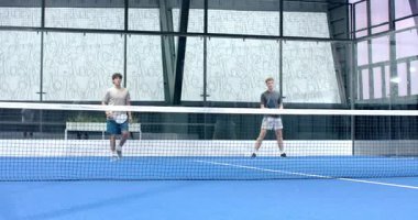 Kapalı alanda tenis oynayan çeşitli erkekler, rekabetçi bir maça odaklanıyor. Spor, rekabet, takım çalışması, raket, fitness, atletik