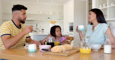 Aile kahvaltısını evde yapıyor, portakal suyu ve ekmek paylaşıyor. Beraberlik, yemek zamanı, kaynaşma, mutfak, yemek, sağlıklı