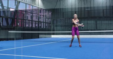 Padel tenis oynayan bir kadın, kapalı sahada raketle topa vuruyor. Spor, atlet, yarışma, fitness, egzersiz
