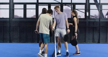 Çeşitli arkadaşlar tenis maçından zevk alıyorlar, raket tutuyorlar, kapalı sahada gülümsüyorlar. Spor, takım çalışması, aktif, eğlence, spor, egzersiz