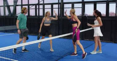 Grup tenis maçının keyfini çıkarıyor, gülümsüyor ve kapalı sahada raket tutuyor. Spor, takım çalışması, eğlence, spor, açık hava, yarışma