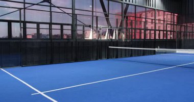 Mavi döşemeli ve geniş pencereli boş padel tenis kortu, kopyalama alanı. Spor, raket, oyun, eğlence, eğlence, fiziksel aktivite