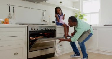 Afro-Amerikan, baba ve kızı, modern mutfakta birlikte yemek pişirmekten zevk alıyorlar. Aile, yakınlaşma, yemek pişirme, birliktelik, mutluluk, yaşam tarzı