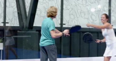 Padel tenisi oynayan genç bir adam, kapalı sahada odaklanma ve kararlılıkla raket sallıyor. spor, atlet, yarışma, konsantrasyon, tutku, eylem