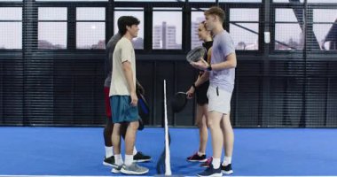 Padel kortunda raket tutan bir grup arkadaş, dostça sohbetin tadını çıkarıyorlar. Spor, arkadaşlık, takım çalışması, eğlence, açık hava, boş zaman