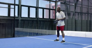 Kapalı alanda tenis oynayan bir adam, topa odaklanarak ve çevikçe vuruyor. Spor, atlet, raket, yarışma, aktif, raket