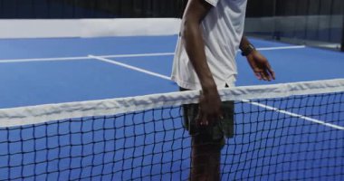 Padel tenis oynayan bir adam, kapalı sahada mavi kortta servis yapmaya hazırlanıyor. Spor, atlet, raket, oyun, aksiyon