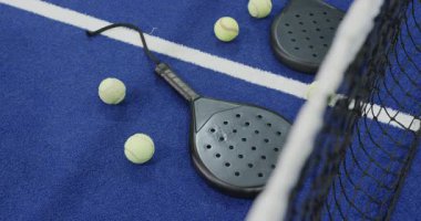 Padel raketler ve toplar mavi sahaya saçılmış, maç için hazırlar. Spor, ekipman, eğlence, rekabet, eğlence, açık hava