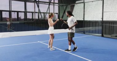 Padel tenis oynuyorlar, çeşitli sporcular mavi sahada raket tutuyor, gülümsüyorlar. raket, spor, eğlence, gençlik, egzersiz, eğlence