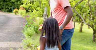 Afro-Amerikalı, baba-kız açık havada eğleniyor, gülücükler ve kahkahalar paylaşıyorlar. Aile, bağ, mutluluk, birliktelik, ebeveynlik