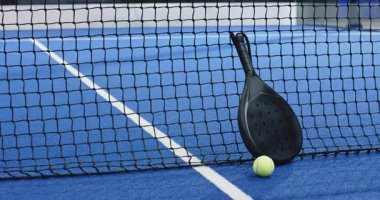 Padel raket ve top mavi sahada ağda dinleniyor, anlaşıldı. Spor, eğlence, rekabet, eğlence, aktif, ekipman