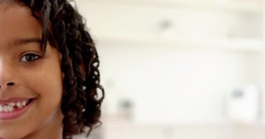 Smiling little girl with curly hair enjoying playful moment at home, copy space. childhood, happiness, leisure, innocence, lifestyle