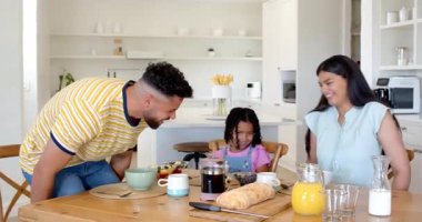 Aile kahvaltıdan keyif alıyor, gülümsüyor ve yemeğini paylaşıyor. Beraberlik, kaynaşma, kahkaha, kapalı alan, yemek, yaşam tarzı