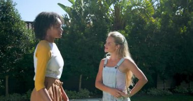 Afrika kökenli Amerikalı kadın ve arkadaş havuz kenarında konuşuyor ve gülüyorlar. Arkadaşlar, eğlence, yaşam tarzı, sohbet, mutluluk, kaynaşma