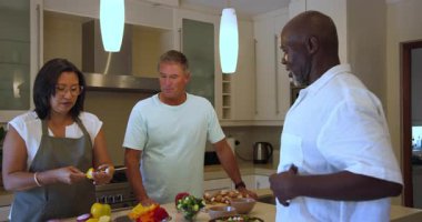 Çeşitli yaşlılar modern mutfakta birlikte sağlıklı yemekler hazırlıyor, evde sohbet ediyorlar. Aşçılık, refah, beslenme, yaşam tarzı, yaşlılık, aşçılık