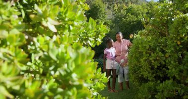 Bahçede, büyükanne ve çocuğu birlikte sulayarak doğanın güzelliğini takdir ediyorlar. Bahçıvanlık, aile, bağ, bahçede, nesilsel, büyüyen