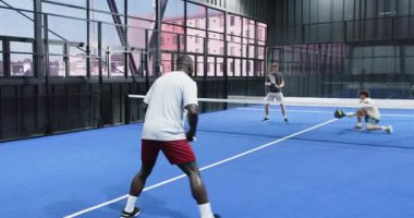Farklı sporcular mavi sahada Padel tenisi oynuyorlar. Rekabetçi ruhlarını gösteriyorlar. Spor, takım çalışması, rekabet, aktif, raket, fitness