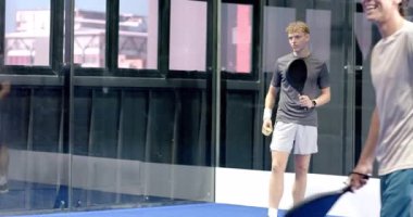 Kapalı sahada Padel tenis oynayan genç adam topa vurmaya odaklanıyor. Spor, egzersiz, raket, kapalı spor, yarışma, atletizm