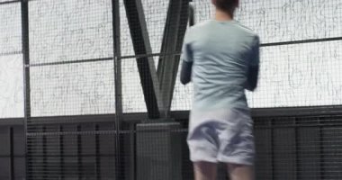 Padel tenisi oynayan genç bir adam, kapalı sahada raketle topa vurmaya odaklanmış. Spor, yarışma, atlet, eğlence, iç saha, takım çalışması