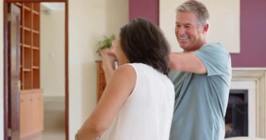 Kıdemli çift evde neşeyle dans ediyor, el ele tutuşuyor ve sıcak bir şekilde gülümsüyor. Son sınıflar, bağlanma, mutluluk, dans, ilişki, yaşam tarzı