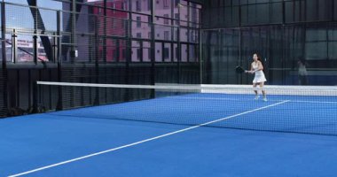 Kadınlar kapalı sahada Padel tenis oynuyorlar, rekabetin tadını çıkarıyorlar. Spor, rekabet, takım çalışması, aktif, boş zaman, eğlence