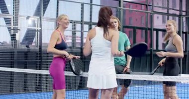 İnsanlar kapalı alanda mavi kortta tenis oynuyorlar, topa vurmaya odaklanıyorlar. Spor, atletizm, rekabet, takım çalışması, koordinasyon, fitness